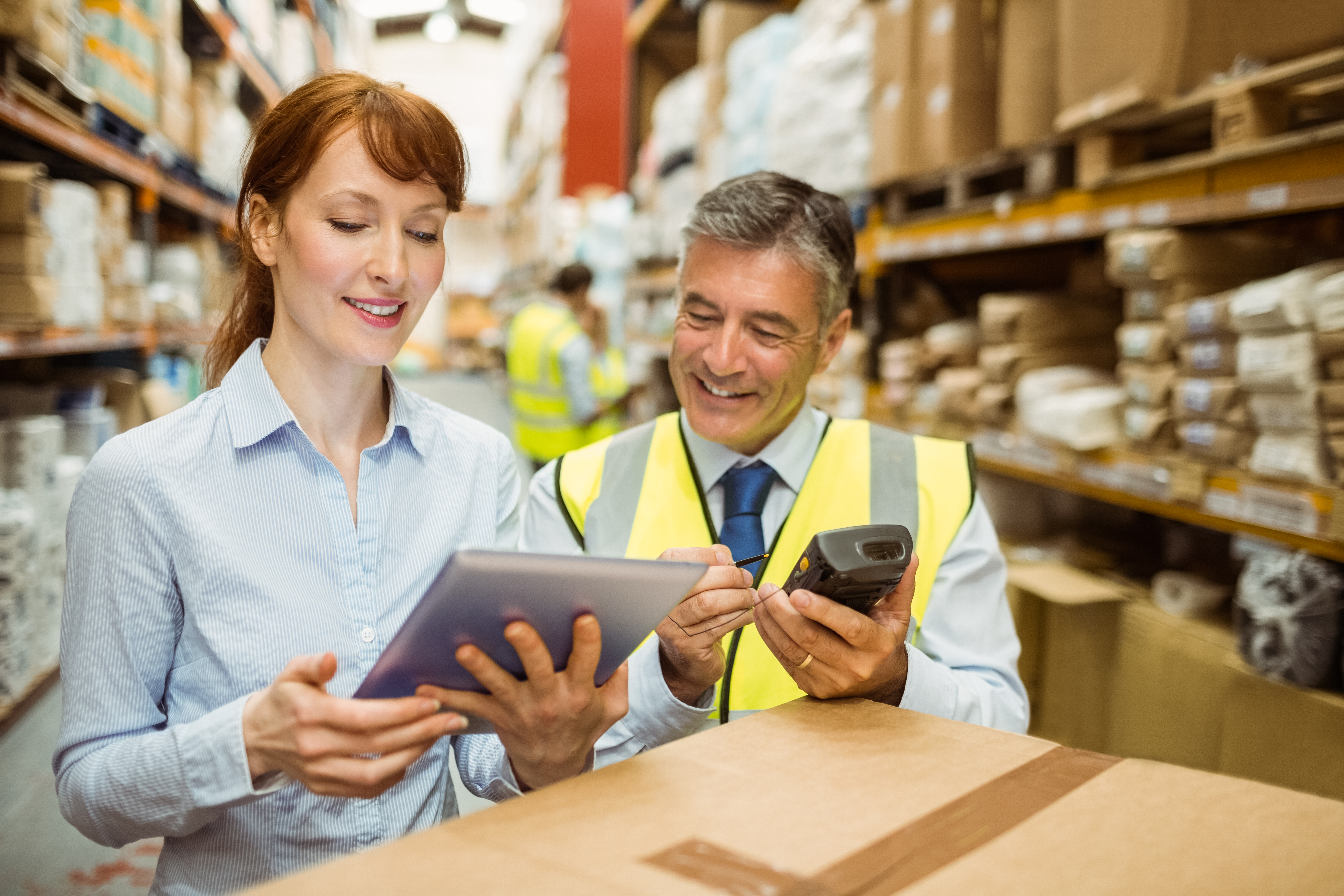 2 people in a warehouse looking at a tablet