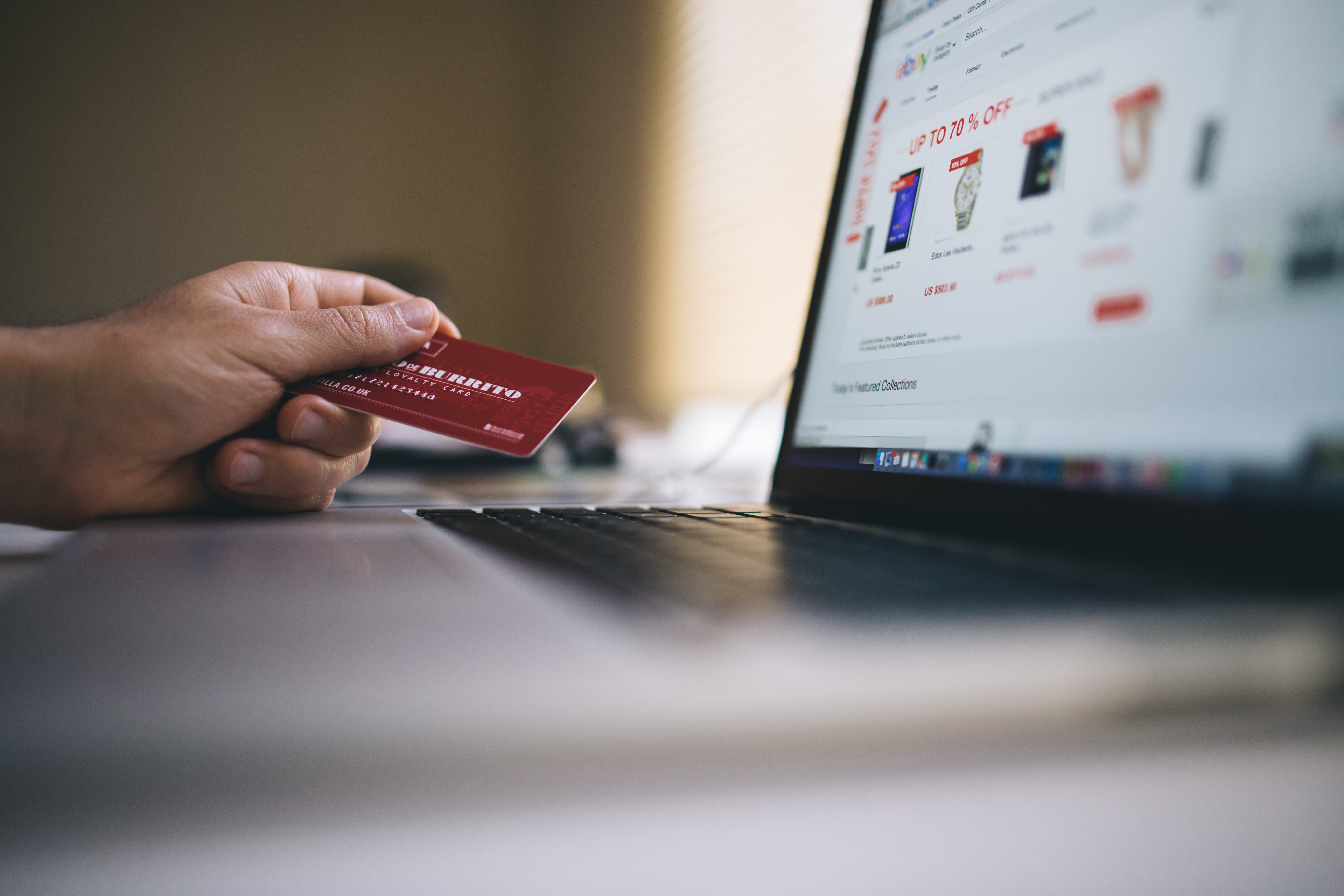 Person holding a credit card next to a laptop