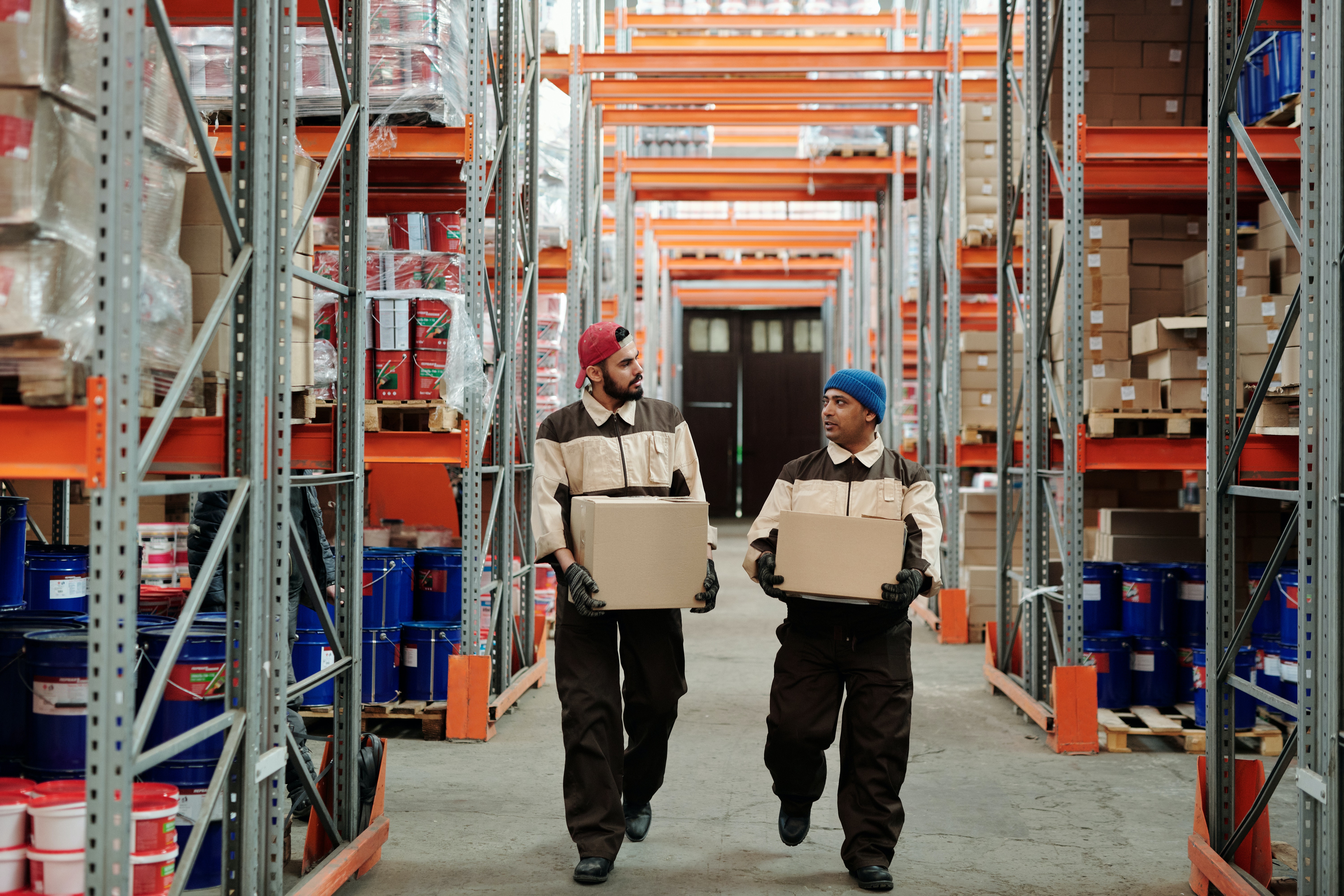 Two people carrying boxes in a warehouse